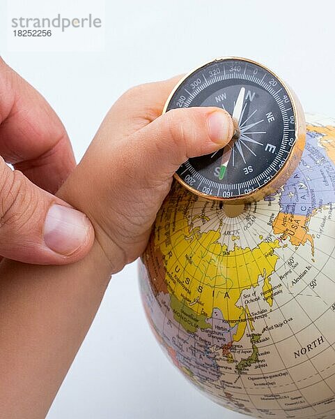 Hand hält einen Kompass und einen Globus auf weißem Hintergrund