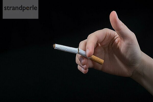 Hand bricht eine Zigarette auf einem schwarzen Hintergrund