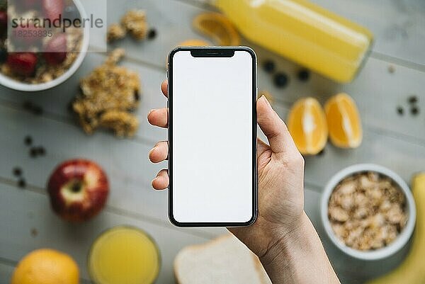 Person hält Smartphone mit leeren Bildschirm Tisch mit Früchten  Auflösung und hohe Qualität schönes Foto