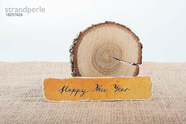 Frohes neues Jahr geschrieben zerrissenes Papier auf Stück Holz