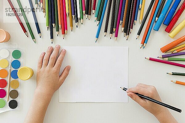 Kind zeichnet mit bunten Stiften