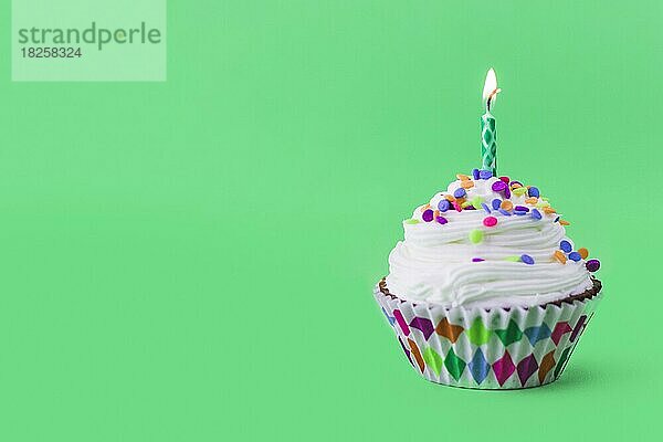 Close up leckeren Cupcake mit brennenden Kerze grünen Hintergrund