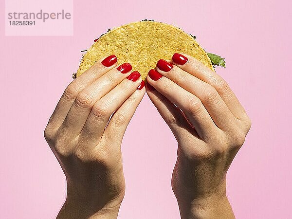 Close up Hände halten Taco mit rosa Hintergrund