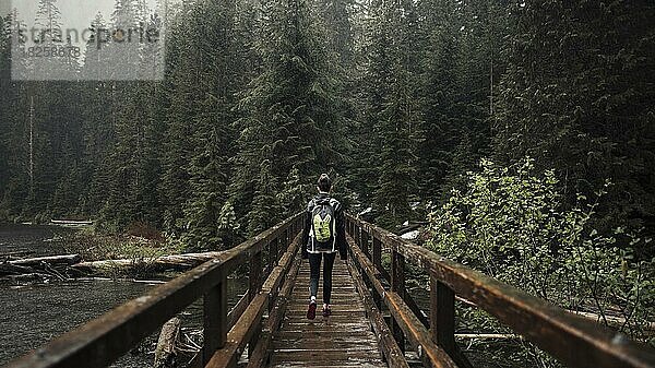 Wanderin auf Holzbrücke in Richtung Wald