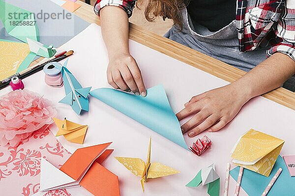 Weibliche Künstlerin faltet Origami-Papier und macht schönes Handwerk