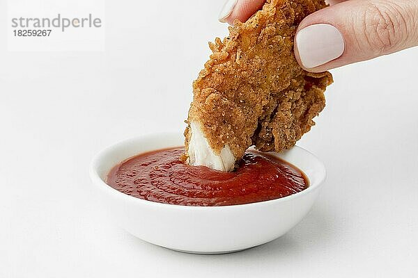 Vorderansicht Hand dipping gebratenes Huhn Ketchup