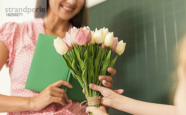 Mädchen überreicht Blumenstrauß ihrem Lehrer
