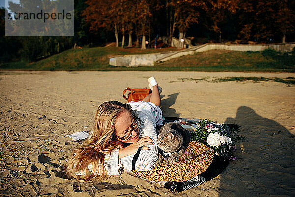 Blonde Frau mit einem Kätzchen am Strand