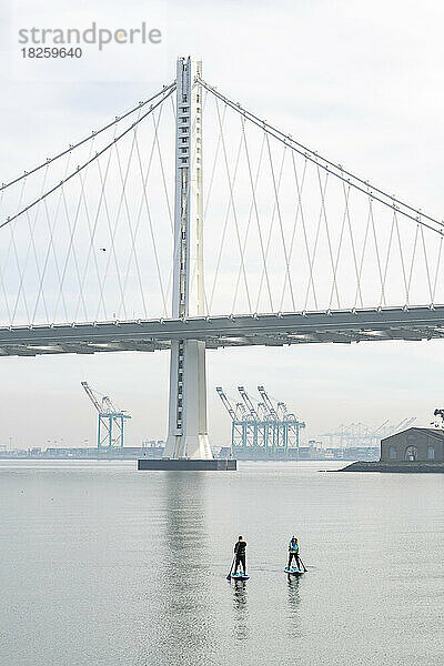 Mann und Frau paddeln in Richtung Oakland Bay Bridge