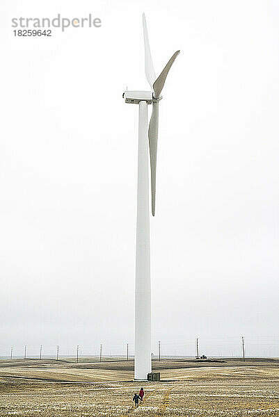 Zwei Kinder gehen auf eine riesige Windmühle zu