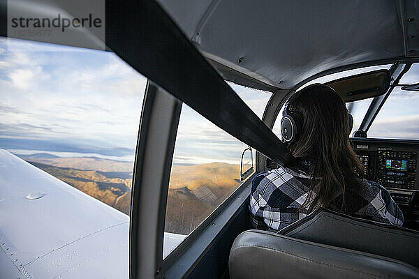 Junge BIPOC-Pilotin fliegt bei Sonnenaufgang ein kleines Flugzeug