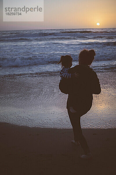 Mutter hält Kind nachts am Strand in Kalifornien