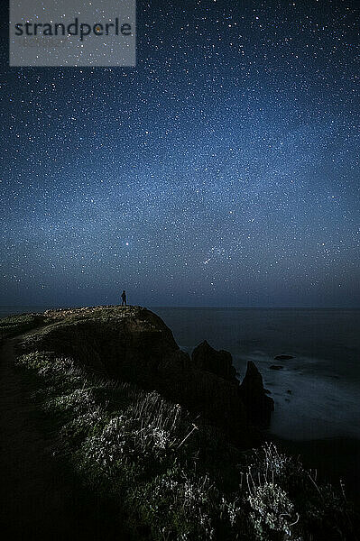 Ein Mann blickt nachts auf den Pazifischen Ozean.
