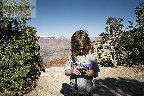 Ein junges Mädchen schaut am Rande des Grand Canyon in eine Filmkamera