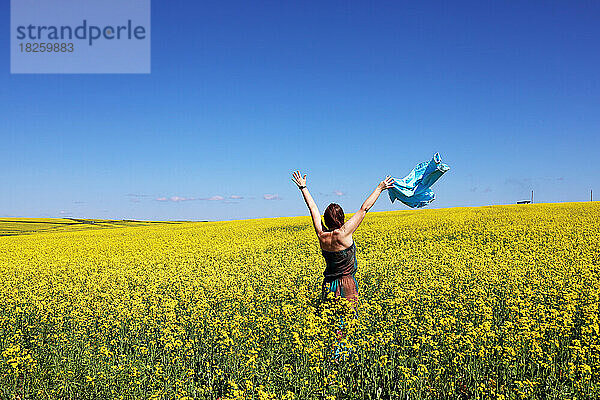 Eine Frau auf einem Feld mit gelben Blumen vor blauem Himmelshintergrund