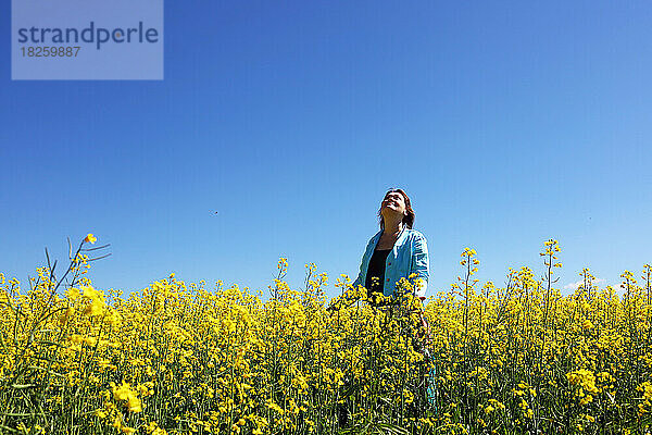 Eine Frau auf einem Feld mit gelben Blumen vor blauem Himmelshintergrund