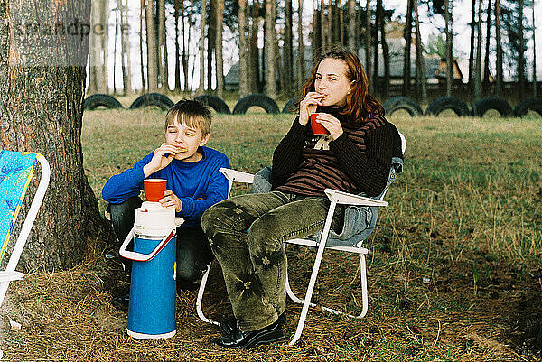 Teenager Bruder und Schwester trinken Tee draußen im Wald