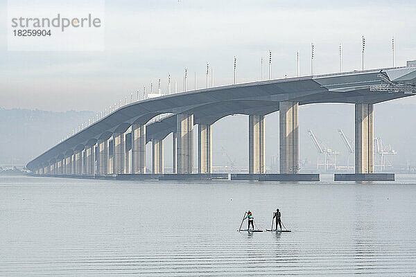 Männliche und weibliche Freunde paddeln in Richtung Oakland Bay Bridge