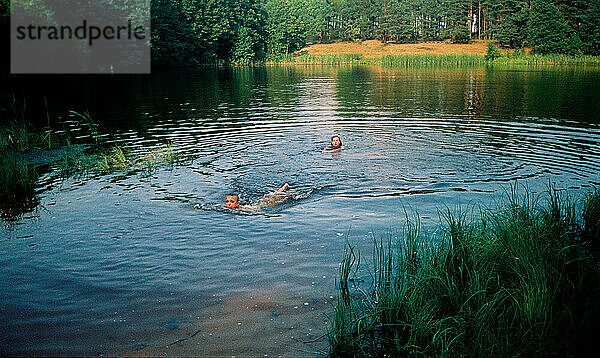 Kinder schwimmen in einem Waldsee