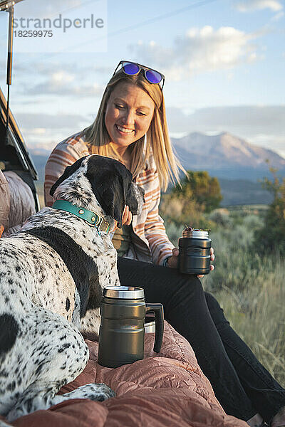 Glückliche Frau streichelt Hund beim Camping im Urlaub