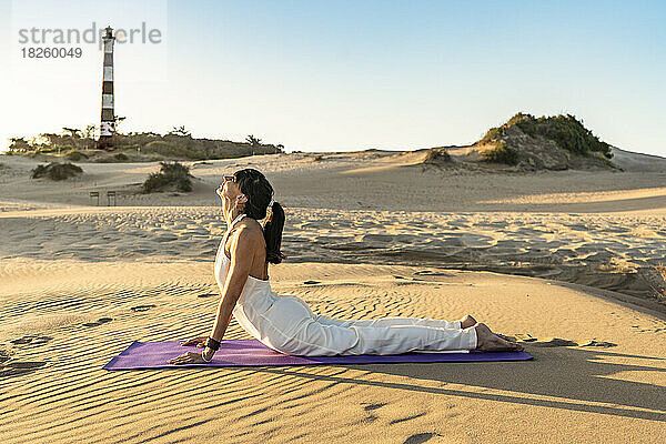 Eine Frau liegt auf einer Matte in einer atemberaubenden Düne in der Nähe eines Leuchtturms