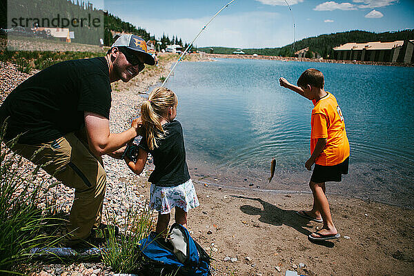 Familie fängt Fische im Urlaub am Seeufer in den Bergen