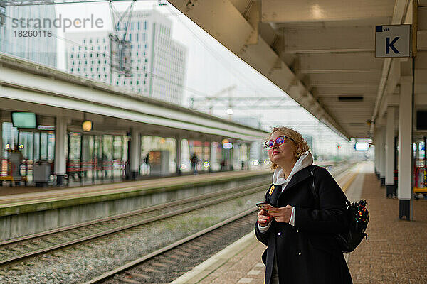 Frau auf dem Bahnsteig am Bahnhof auf der Suche nach dem Zug