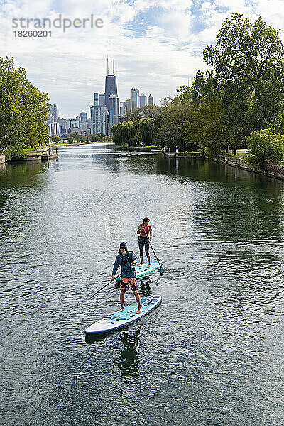 Mann und Frau paddeln im Fluss mit der Stadt im Hintergrund