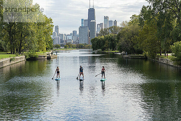 Freunde paddeln im Fluss mit der Stadt im Hintergrund