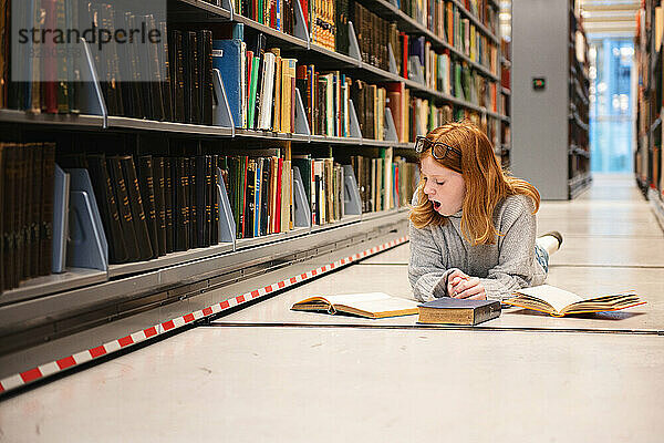 Müdes Teenager-Mädchen lernt in der Bibliothek.