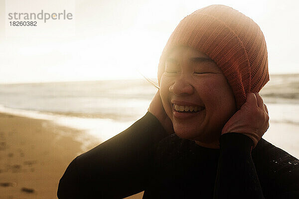schöne asiatische Frau hält ihren Hut zum Schwimmen im kalten Wasser bereit