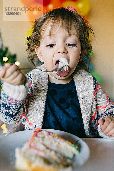 Kleines Mädchen isst ein Stück Geburtstagstorte