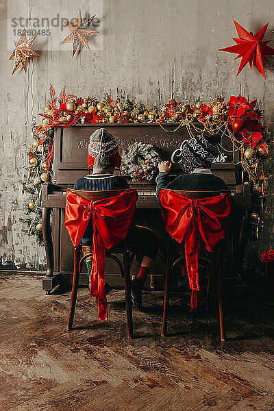 Jungen spielen auf dekoriertem Weihnachtsklavier