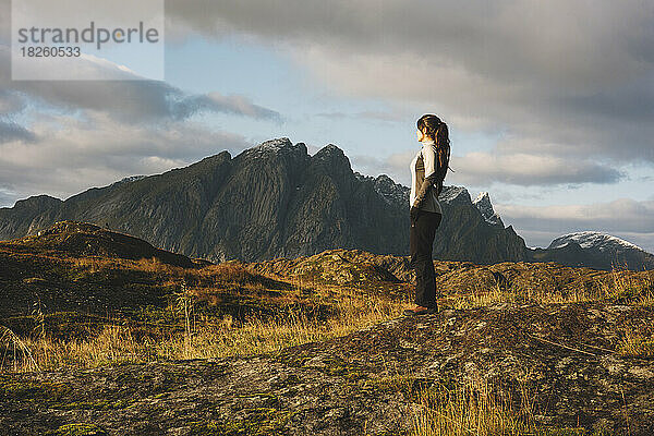 Frau blickt bei Sonnenuntergang auf den Berg