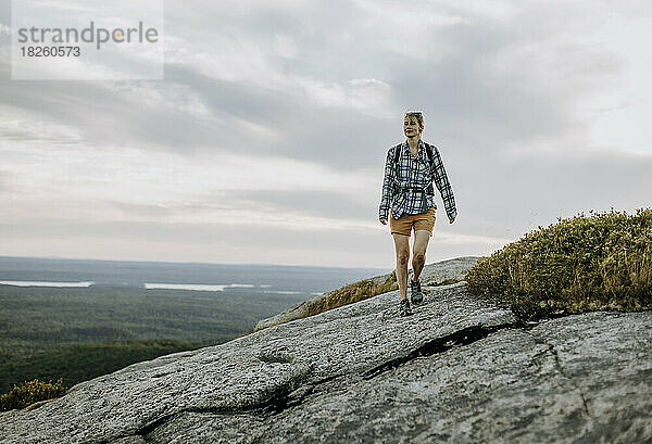 Junge Frau im Flanellhemd wandert entlang des Schoodic Mountain  Maine