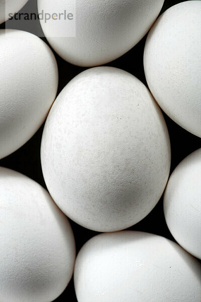 Weiße Eier auf einem schwarzen Tisch.