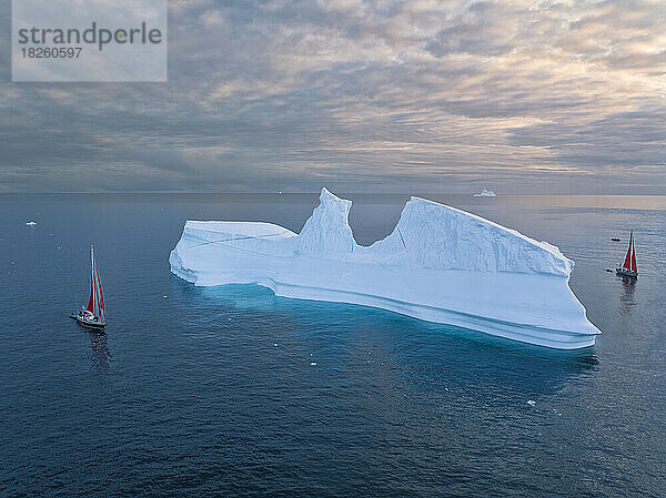 Kleine Segelboote in der Nähe großer Eisberge aus der Luft