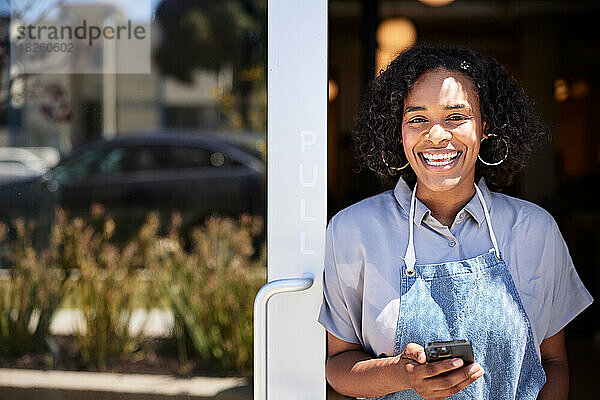 Porträt einer glücklichen Unternehmerin mit Smartphone