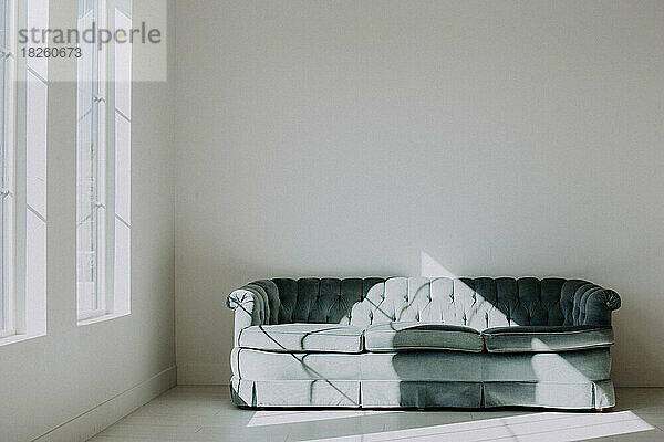 Blaue Midevil-Couch in einem minimalistischen  weißen Raum mit natürlichem Licht
