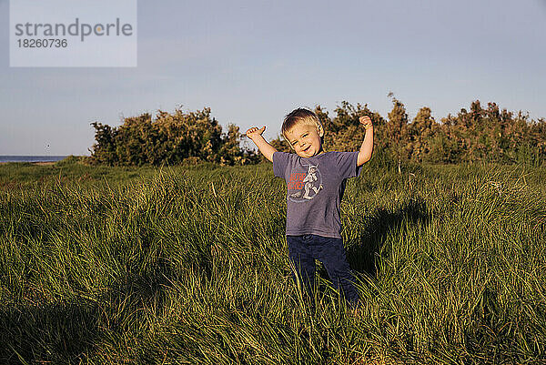 Ein kleiner Junge lächelt auf einer Wiese an der Küste