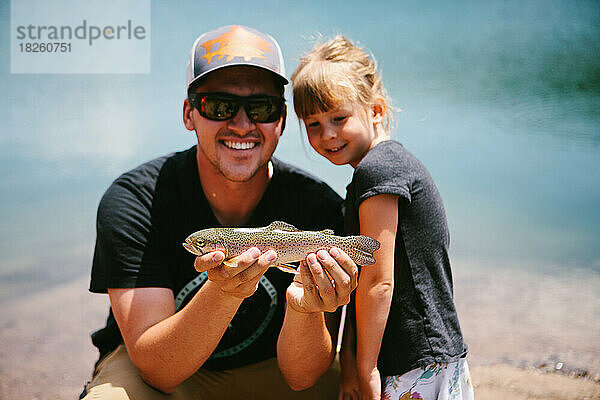 Mann und Mädchen mit einem Fisch  den sie im Bergteich gefangen haben