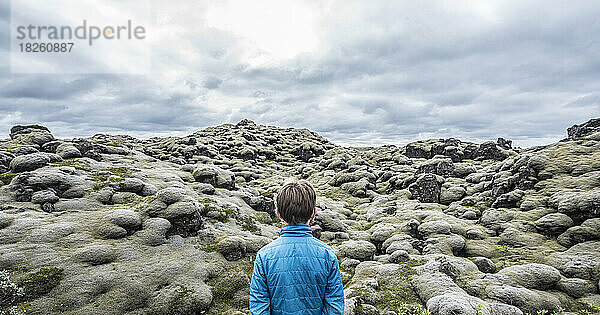 Ein Junge wandert in moosbedeckten Lavafeldern im Süden Islands