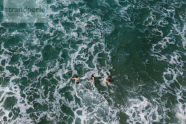 Teenager schwimmen im Sommerurlaubsabenteuer in den Wellen des Ozeans