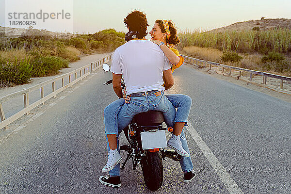 Junges Paar reist glücklich mit dem Motorrad auf der Straße im Freien.
