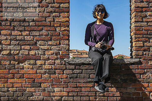 Frau sitzt auf einer Mauer auf der Brücke Ponte Pietra