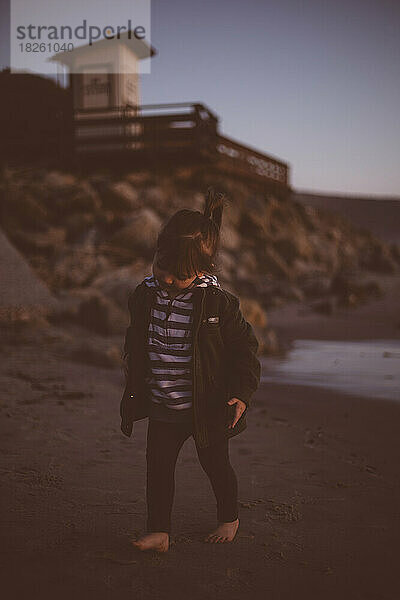 Kleines Mädchen läuft in einer kalten Nacht in Kalifornien am Strand