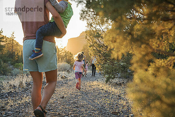 Eine Mutter geht mit Kindern bei Sonnenuntergang einen Pfad entlang