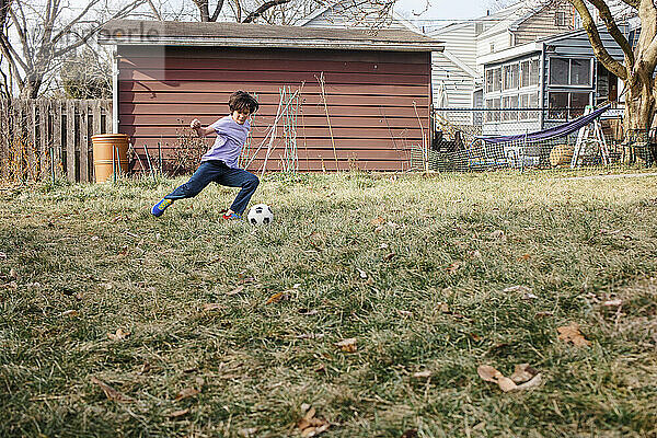 Ein athletischer Junge kickt allein im Hinterhof Fußball