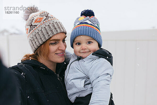 Mutter und kleiner Junge machen draußen im Schneefall gemeinsam ein Selfie