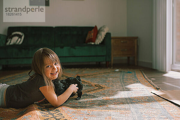 Kind spielt mit schwarzem Malteserwelpen in einem Zimmer im Boho-Stil